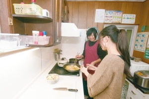 福祉施設で学生が料理を教わっている写真